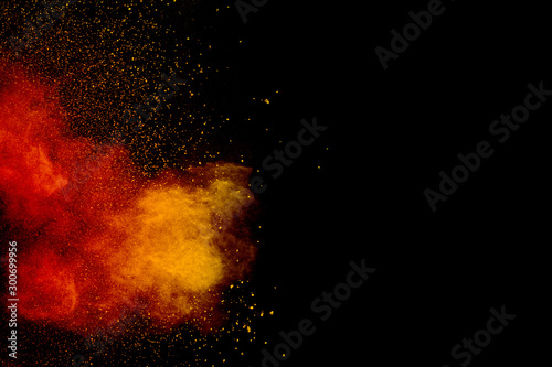 Orange red powder explosion on black background.Orange red color dust splash clouds.