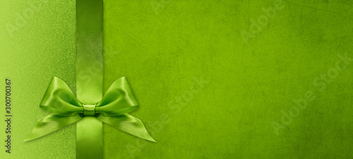 christmas gift card with green ribbon bow on green background, copy space template
