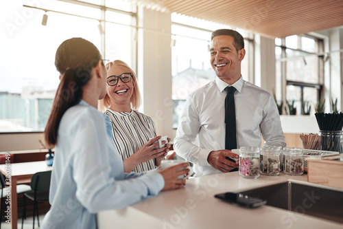 Laughing businesspeople talking during their office coffee break