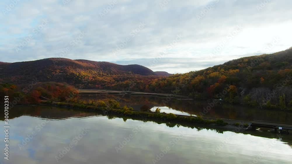Smooth push in aerial of train tracks and Hudson River Valley mountains colorful fall foliage reflections on water Smooth push in aerial of train tracks and Hudson River Valley mountains colorful fall foliage reflections on water