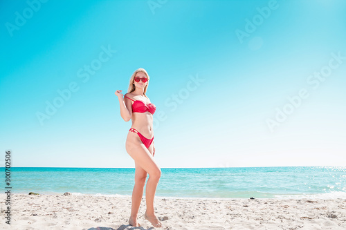 Portrait of a blonde in pink glasses at the sea. A woman walks along the beach and enjoys.