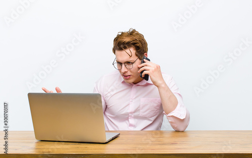 young red head businessman working in his desk with a monile phone photo