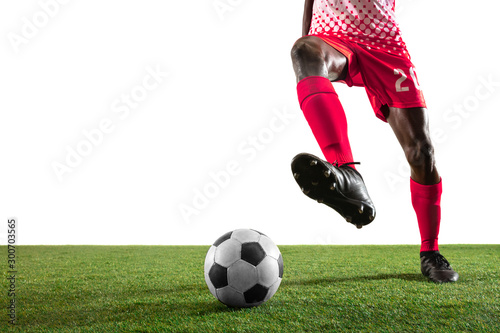 Fototapeta Naklejka Na Ścianę i Meble -  Professional african-american football or soccer player of red team in motion isolated on white studio background. Fit man in action, excitement, emotional moment. Concept of movement at gameplay.