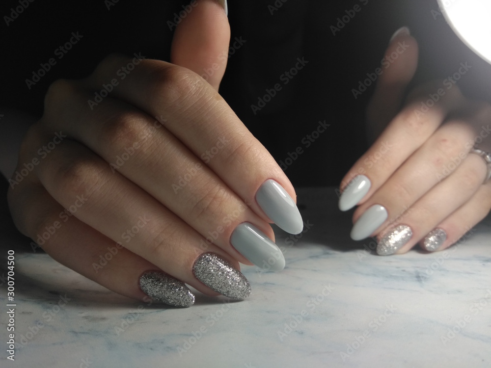 Glossy light grey gel Polish with glitter design. Grey coating on long nails with silver design. Christmas bright for the holiday. Stock Photo | Adobe Stock