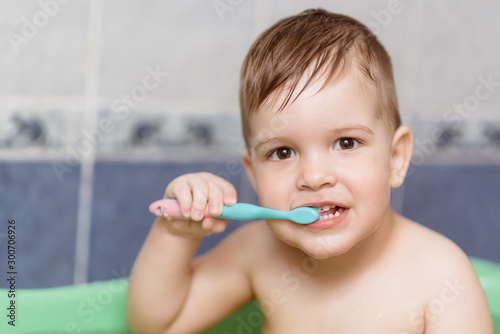 lovely baby brushing his teeth with a toothbrush in the bathroom