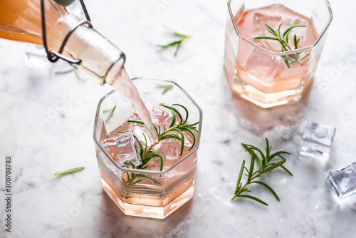 Pink grapefruit and rosemary drink, backlight on white background