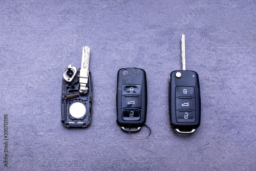 Broken or damaged remote key fob and new vehicle key on gray background. Broken or damaged remote key fob of any vehicle car service.- Image