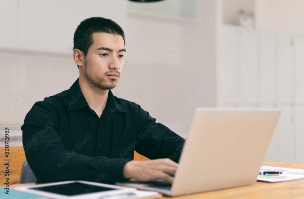 Portrait of a young business man using laptop computer while working. Young asian business men working with laptop in coffee shop cafe. Portrait of a young business man using laptop computer while working. Young asian business men working with laptop in coffee shop cafe.