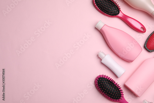 Flat lay composition with hair cosmetic products and tools on pink background. Space for text