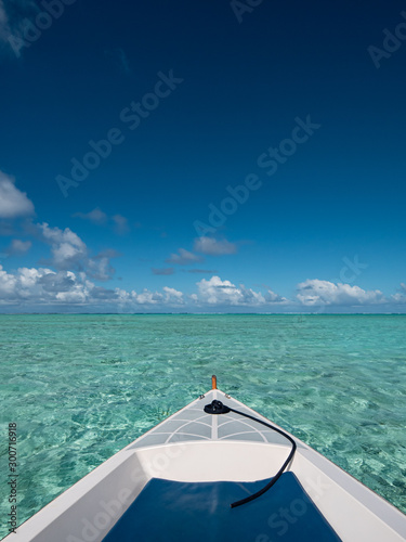 Sailing a boat around blue lagoon and luxury overwater villas at Bora Bora island, Tahiti, French Polynesia