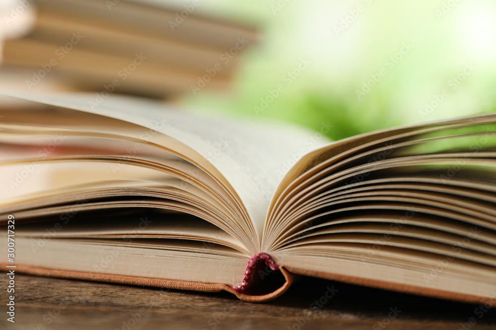 Open hardcover book on wooden table against blurred background, closeup Open hardcover book on wooden table against blurred background, closeup