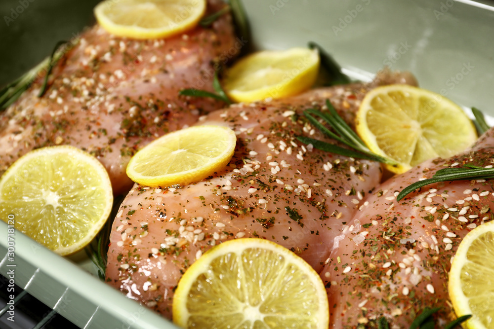 Chicken breasts with lemon and rosemary in baking dish, closeup Chicken breasts with lemon and rosemary in baking dish, closeup