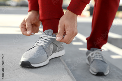Fototapeta Naklejka Na Ścianę i Meble -  Sporty man tying shoelaces before running outdoors