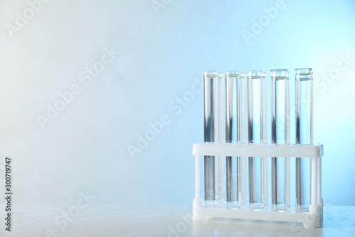 Test tubes with liquid samples on table against toned blue background  space for text. Laboratory analysis