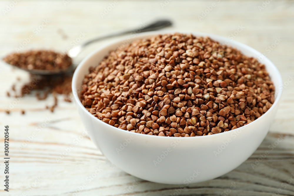 Bowl of uncooked buckwheat on white wooden table Bowl of uncooked buckwheat on white wooden table