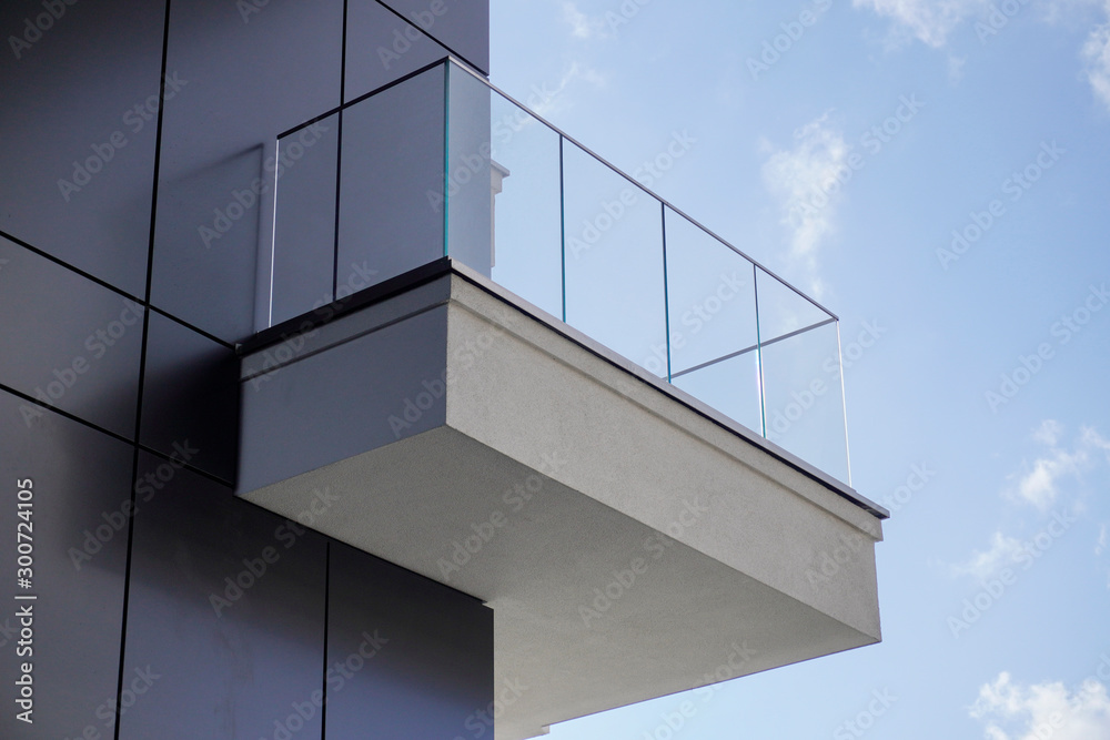 one open balcony or terrace on the facade of a concrete modern house against a background of blue sky with white clouds. one open balcony or terrace on the facade of a concrete modern house against a background of blue sky with white clouds.