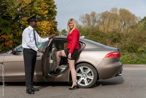 Andover, Hampshire, UK. October 2019.  Blond female passenger wearing a short skirt and a smartly dressed chauffeur speaking to the client. © petert2