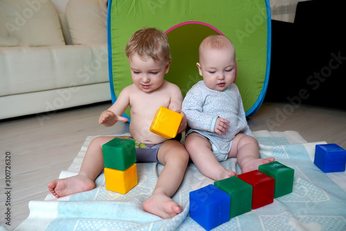 Little children sit on the floor and have fun playing cubes. Childhood concept