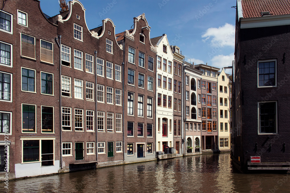 View of historical, traditional and typical buildings showing Dutch architectural style in Amsterdam at Armbrug bridge area. It is a sunny summer day.
