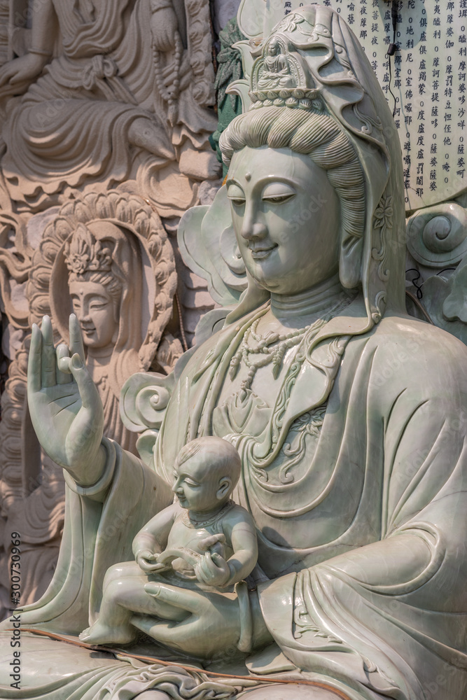 Da Nang, Vietnam - March 10, 2019: Chua An Long Chinese Buddhist Temple. Closeup of greenish marble statue of Guam Yin bust with child on lap.