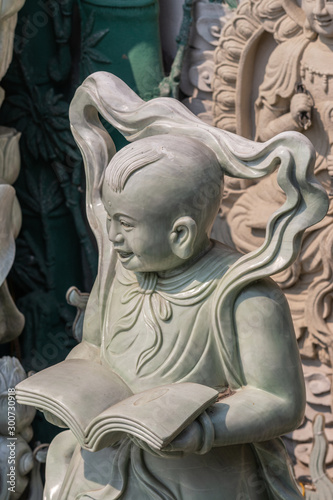 Da Nang  Vietnam - March 10  2019  Chua An Long Chinese Buddhist Temple. Closeup of greenish marble statue of singing child with book at side of Guan Yin statue  not in picture.