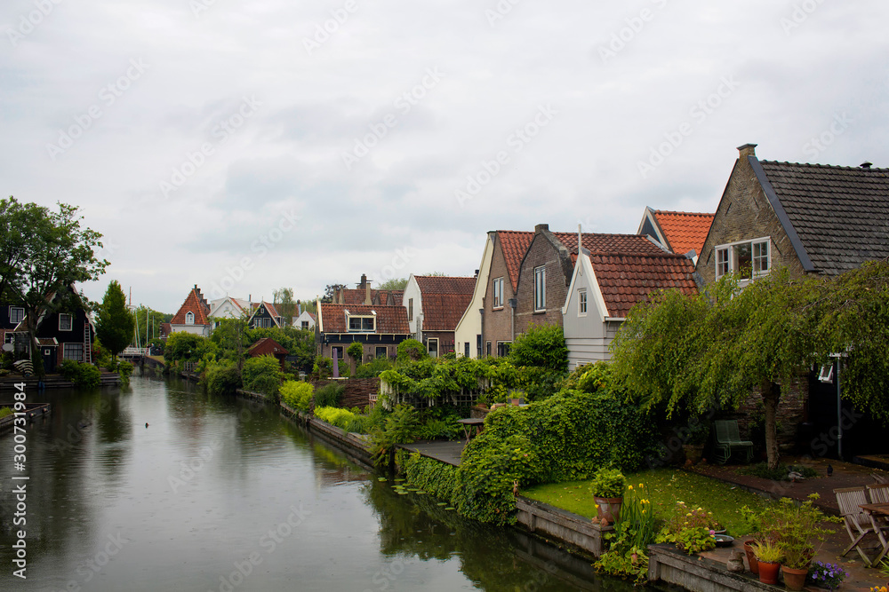 View of traditional houses, trees, plants and canal in Edam. It is a town famous for its semi hard cheese in the northwest Netherlands, in the province of North Holland.