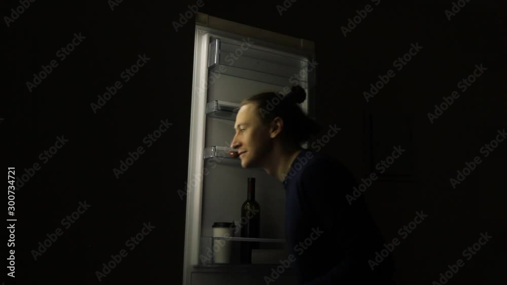 Hungry Man with eating disorder Looking in a Fridge Taking Food at Night. Concept of unhealthy lifestyle Hungry Man with eating disorder Looking in a Fridge Taking Food at Night. Concept of unhealthy lifestyle