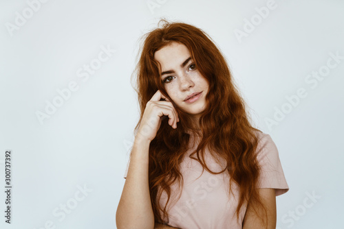 schoolgirl with a pensive look propped her hand on her cheek in a light color studio