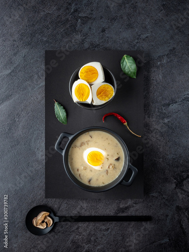 Mushroom cream soup with boiled eggs on black background. Overhead shot. photo