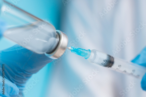 Doctor hand holding syringe and vaccine in blue gloves white coat. Disease injection concept