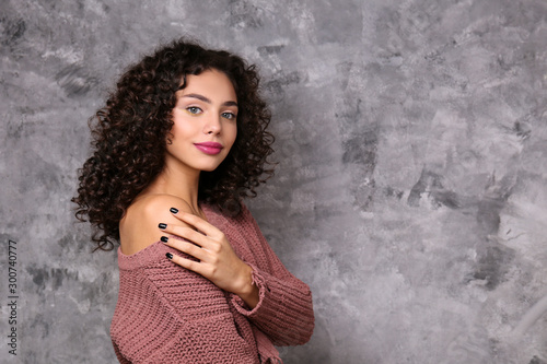 Portrait of happy beautiful woman with long bouncy curles hairstyle and professional make up on, posing over grunged stone background. Fashion shot of young gorgeous female. Close up, copy space.