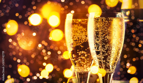 Two champagne glasses and christmas decoration on wooden snow golden bokeh background. Happy New Year Celebration. Selective focus and small depth of field