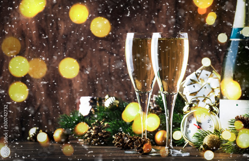 Two champagne glasses and christmas decoration on wooden snow golden bokeh background. Happy New Year Celebration. Selective focus and small depth of field