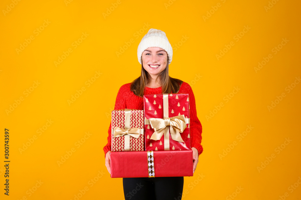 Close up portrait of young beautiful woman with light make up on, wearing knitted sweater & white woolen beanie. Attractive female in winter knitwear outfit, isolated on yellow background. Copy space
