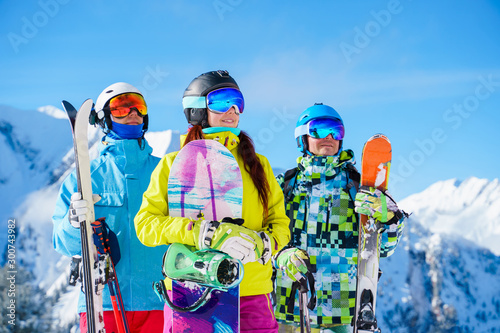 Image of sports woman and men with skis and snowboard standing at ski resort