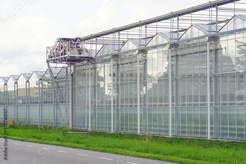 Glasshouses or greenhouses for growing vegetables against sky. On the outside of the greenhouses in The Netherlands. High tech industrial production of vegetables and flowers.