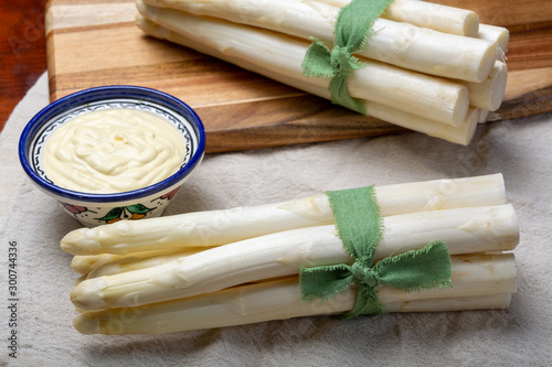 Bunch of fresh uncooked white asparagus and hollandaise sauce in bowl photo