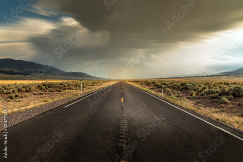 Long straight road in Utah with dramatic clouds and rain rolling in