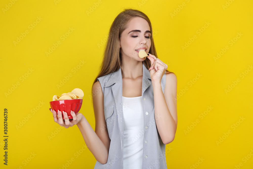 Young beautiful girl eating potato chips on yellow background Young beautiful girl eating potato chips on yellow background