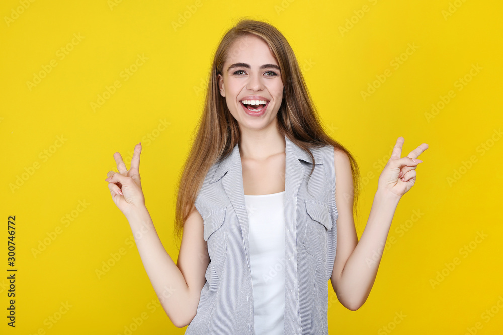 Young beautiful girl gesturing with hands on yellow background Young beautiful girl gesturing with hands on yellow background