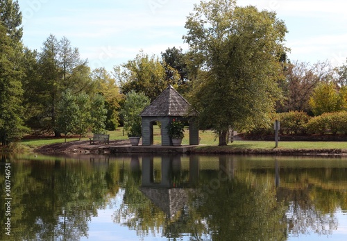 The gazebo and trees reflect off the water of the lake.