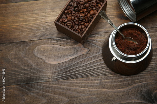 ground coffee in a coffee maker with a teaspoon on a wooden background with copy space. background with roasted coffee grains. 