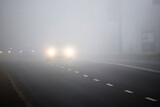 Motion of cars with headlights on during heavy fog_