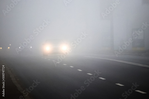 Motion of cars with headlights on during heavy fog_