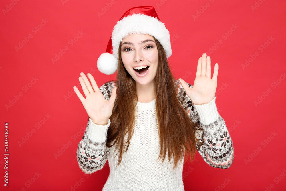 Beautiful woman in sweater and santa hat on red background Beautiful woman in sweater and santa hat on red background