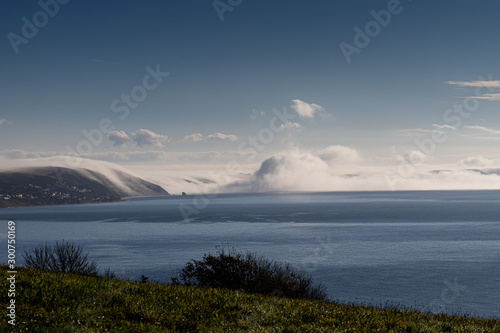 Clouds forming from mist flowing over the cliffs in Whitsand bay Cornwall