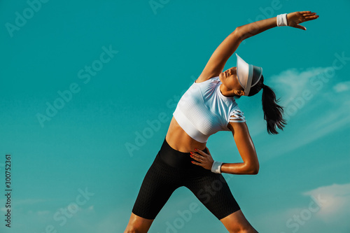 Individual sports recreation. Sporty and fit young woman athlete doing yoga training on the sky background. The concept of a healthy lifestyle and sport.