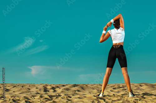 Sporty and fit young woman athlete doing yoga training on the sky background. The concept of a healthy lifestyle and sport. Individual sports recreation.