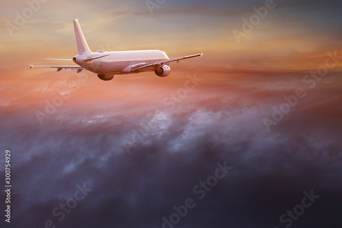 Samolot komercyjny lecący nad dramatyczne chmury podczas zachodu słońca.
