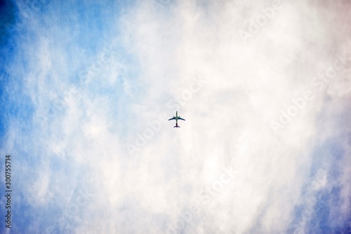 Low angle shot of an airplane flying high in the sky with pure white clouds